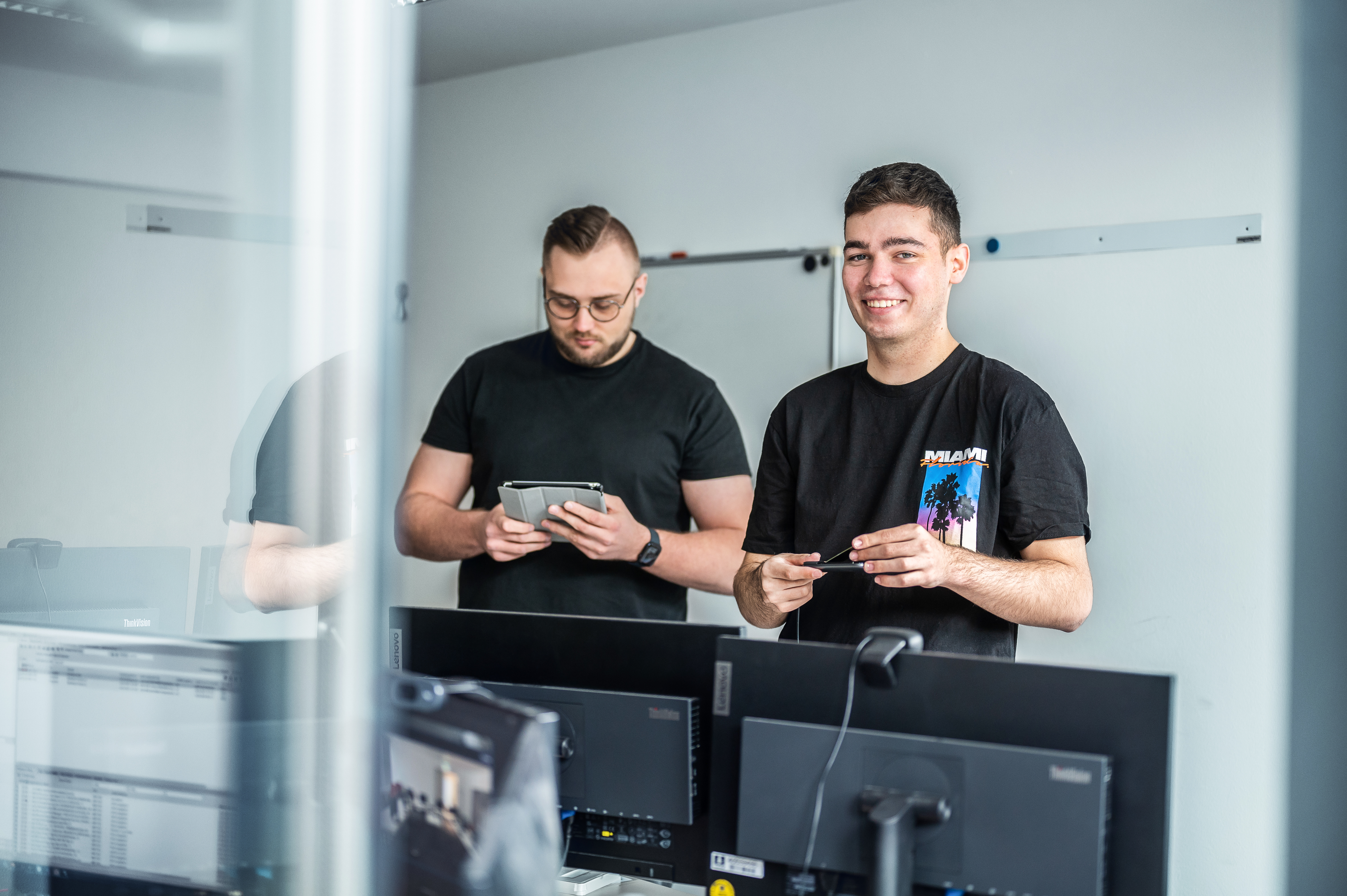 Two young men work on digital devices