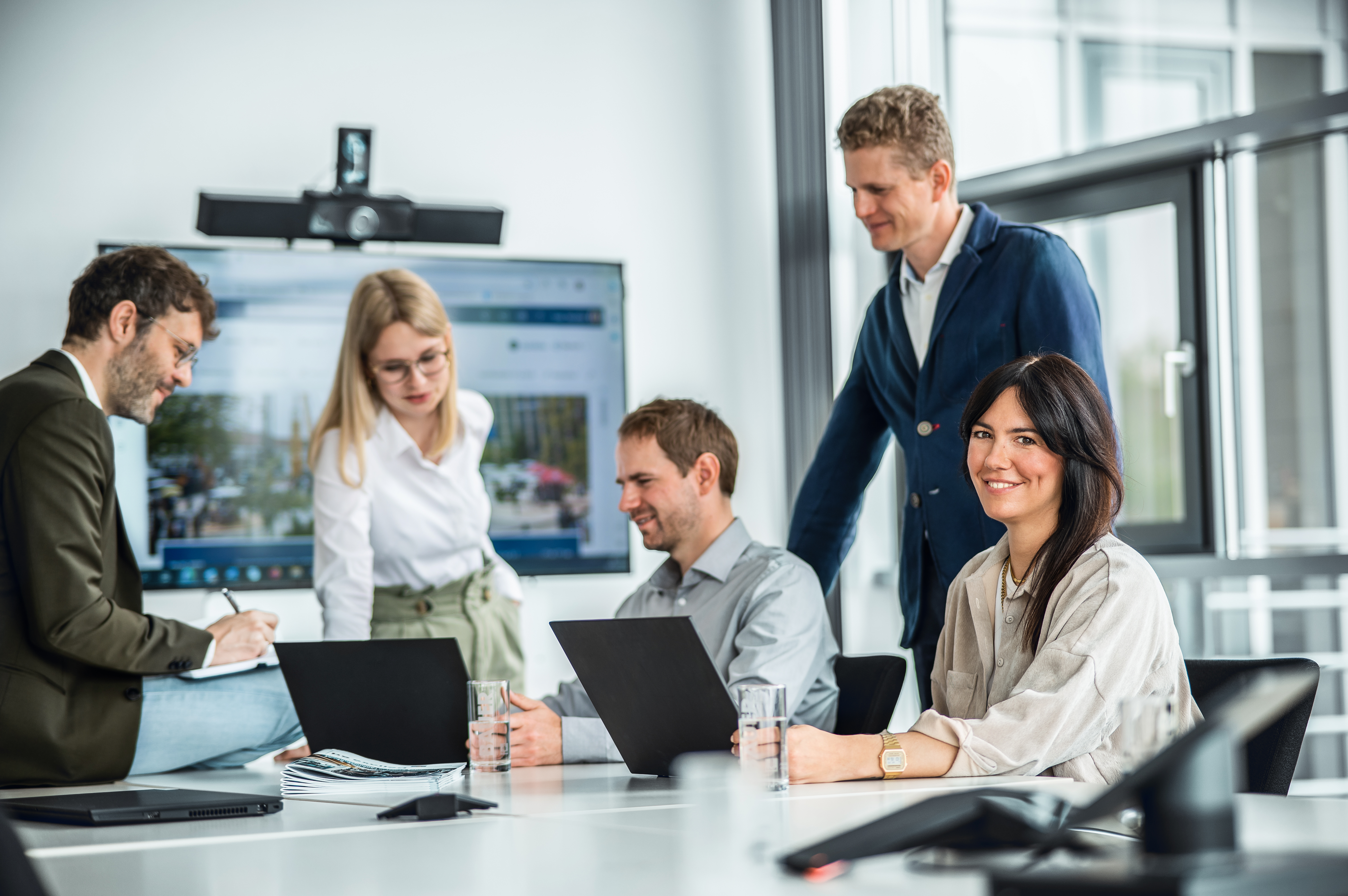 A team in a meeting, with a young woman smiling at the camera