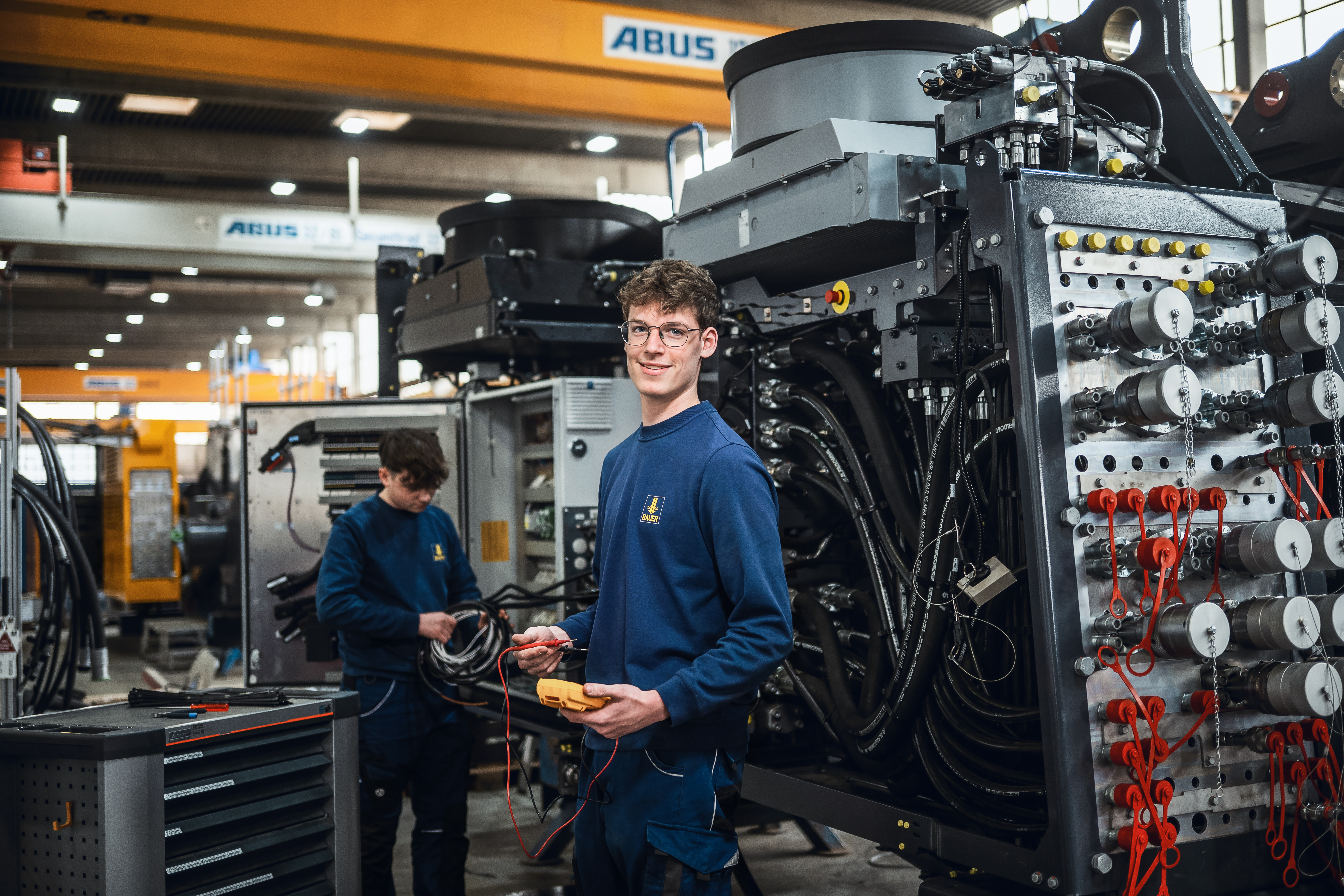 Junger Mann vor einer Maschine, der Verantwortung bei BAUER übernimmt