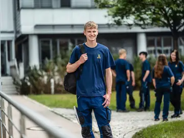 Valentin Greger, apprentice industrial mechanic at Bauer, outside with colleagues in the background.