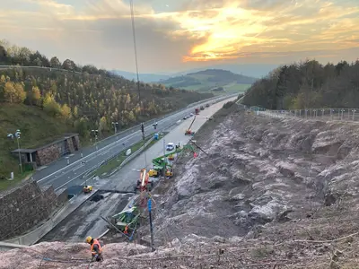 Im Rahmen der Fahrbahnerneuerung an der A38 südlich von Göttingen waren umfangreiche Sicherungsmaßnahmen der umliegenden Felswände notwendig. Von September 2020 bis Juni 2021 führte die Spesa hier 6.000 lfm Bodenvernagelung sowie 16.000 m² Steinschlag-schutznetze aus. Ein eindrucksvolles Beispiel für Sicherheit, Effizienz und langlebige Qualität.